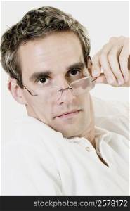 Portrait of a mid adult man peeking over his eyeglasses