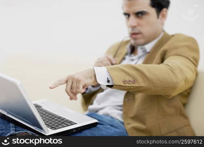 Portrait of a mid adult man pointing at a laptop