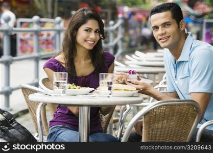 Portrait of a mid adult man proposing to a young woman at a sidewalk cafe