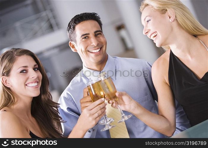 Portrait of a mid adult man raising a toast with two young women