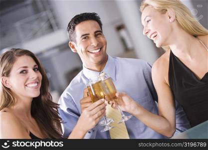 Portrait of a mid adult man raising a toast with two young women