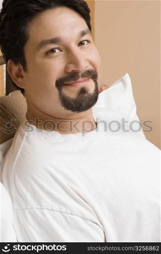 Portrait of a mid adult man reclining on the bed and smiling