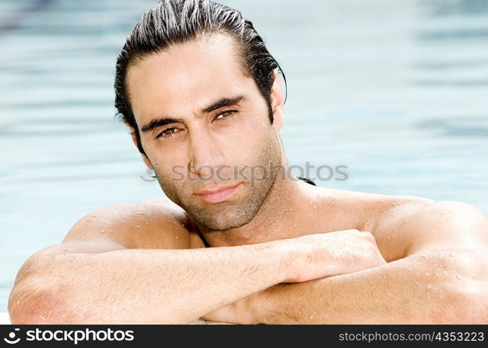 Portrait of a mid adult man resting his arms on the edge of a swimming pool