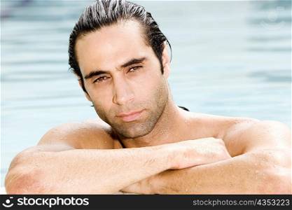 Portrait of a mid adult man resting his arms on the edge of a swimming pool