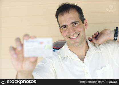 Portrait of a mid adult man showing a credit card and smiling
