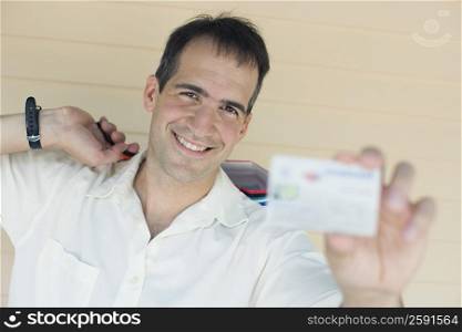 Portrait of a mid adult man showing a credit card and smiling