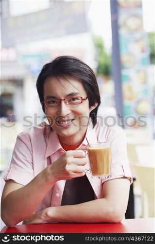 Portrait of a mid adult man sitting in a cafe and holding a mug of coffee