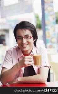 Portrait of a mid adult man sitting in a cafe and holding a mug of coffee