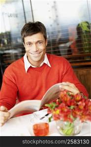Portrait of a mid adult man sitting in a restaurant holding a menu