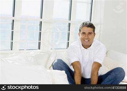 Portrait of a mid adult man sitting on a bed