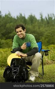 Portrait of a mid adult man sitting on a chair holding a coffee cup