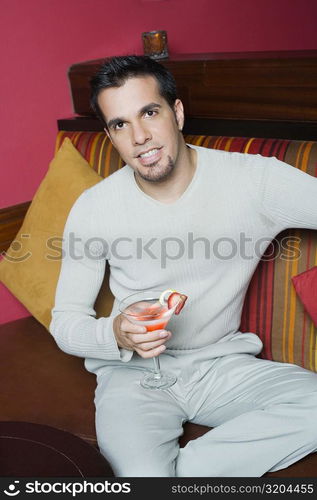 Portrait of a mid adult man sitting on a couch and holding a cocktail