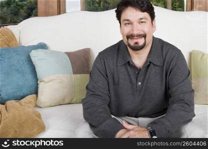 Portrait of a mid adult man sitting on a couch and smirking