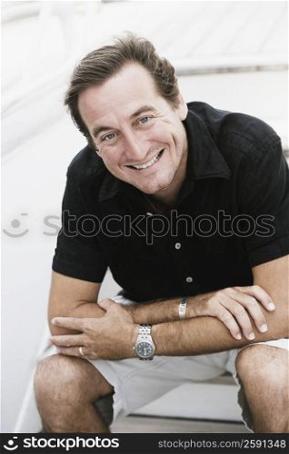 Portrait of a mid adult man sitting on a staircase and smiling