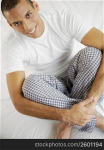 Portrait of a mid adult man sitting on the bed and smiling