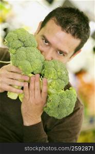 Portrait of a mid adult man smelling broccolis