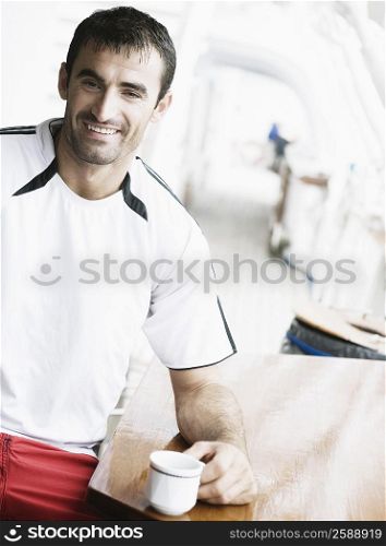 Portrait of a mid adult man smiling and holding a cup of tea