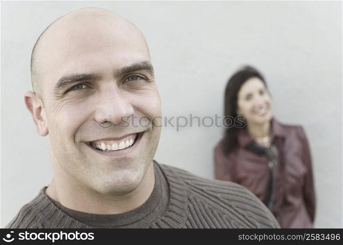 Portrait of a mid adult man smiling with a mature woman in the background