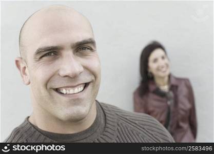 Portrait of a mid adult man smiling with a mature woman in the background