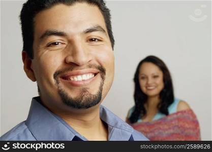 Portrait of a mid adult man smiling with a mid adult woman in the background