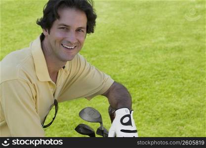 Portrait of a mid adult man smiling with golf clubs
