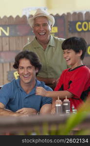 Portrait of a mid adult man smiling with his father and son in a restaurant