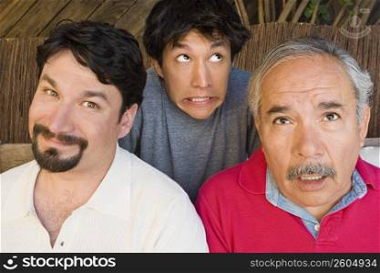 Portrait of a mid adult man smirking with his father and son making their faces