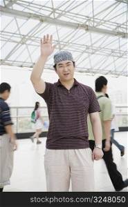 Portrait of a mid adult man standing in a corridor and waving his hand