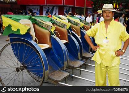 Portrait of a mid adult man standing near pedicabs, Nanjing, Jiangsu Province, China