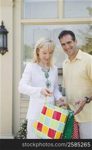 Portrait of a mid adult man standing with a mid adult woman looking into a bag