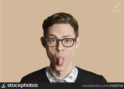 Portrait of a mid adult man sticking out tongue over colored background