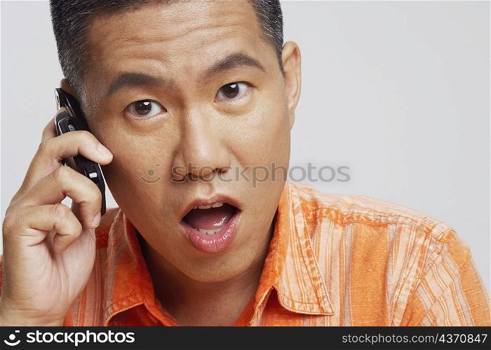 Portrait of a mid adult man talking on a mobile phone and looking surprised