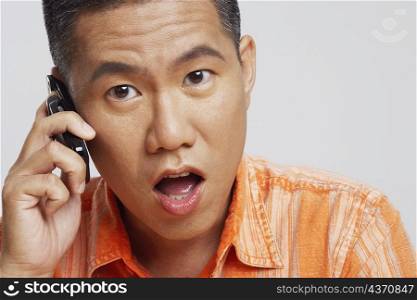 Portrait of a mid adult man talking on a mobile phone and looking surprised