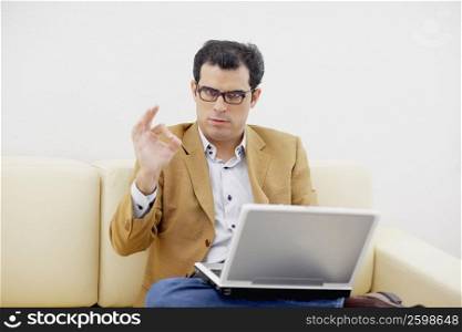 Portrait of a mid adult man using a laptop and gesturing