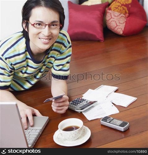 Portrait of a mid adult man using a laptop and holding a credit card