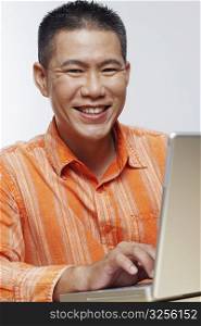 Portrait of a mid adult man using a laptop and smiling