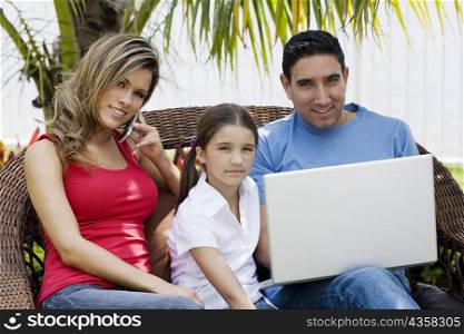 Portrait of a mid adult man using a laptop with a girl and a young woman sitting beside them
