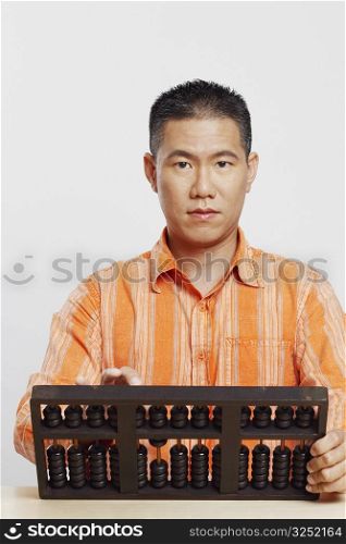 Portrait of a mid adult man using an abacus