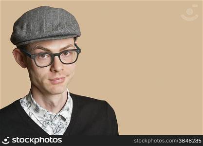 Portrait of a mid adult man wearing retro glasses and cap over colored background