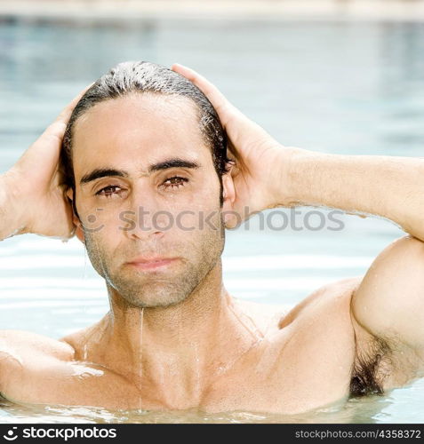 Portrait of a mid adult man with his hands on his head in a swimming pool