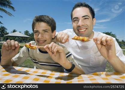 Portrait of a mid adult man with his son eating sausages in a picnic