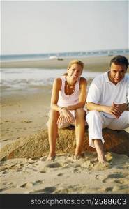 Portrait of a mid adult woman and a mature man sitting on the beach
