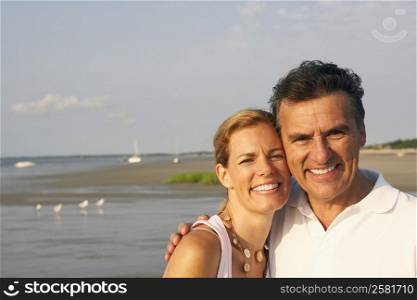 Portrait of a mid adult woman and a mature man standing on the beach and smiling