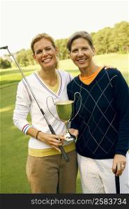 Portrait of a mid adult woman and a mature woman holding a trophy