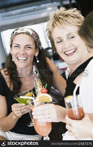 Portrait of a mid adult woman and a mature woman holding glasses of cocktail and smiling