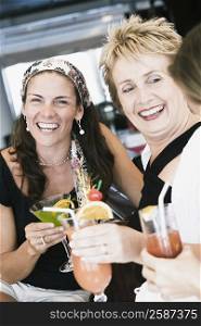 Portrait of a mid adult woman and a mature woman holding glasses of cocktail and smiling