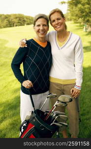 Portrait of a mid adult woman and a mature woman holding golf clubs