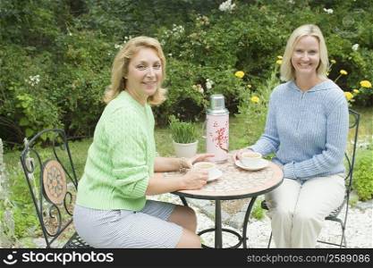 Portrait of a mid adult woman and a mature woman sitting together in a tea party