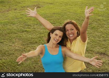 Portrait of a mid adult woman and a mature woman standing with their arms outstretched