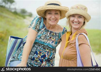 Portrait of a mid adult woman and a mature woman wearing a straw hat and smiling